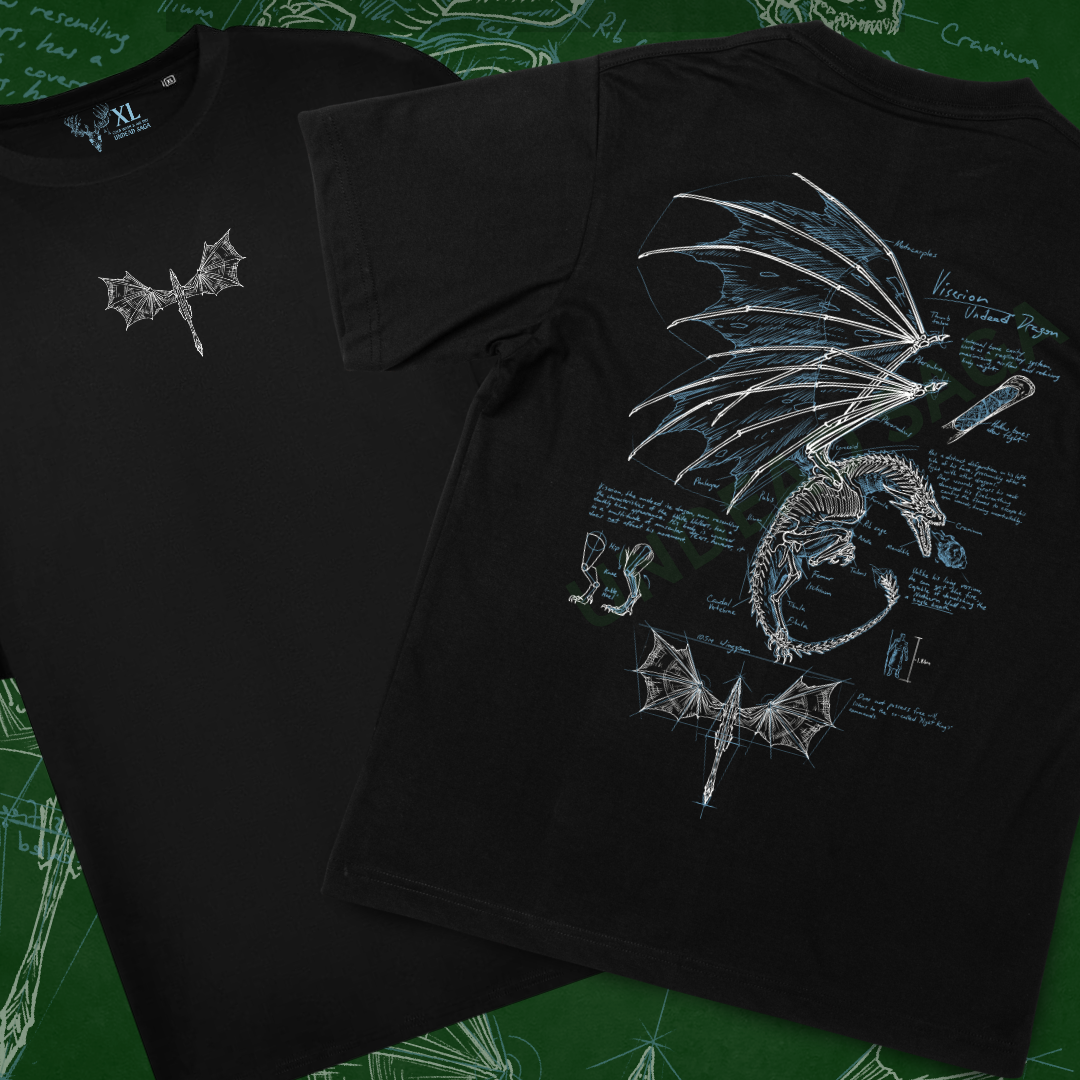 Two black graphic T-shirts displayed on a green chalkboard-style background. The front shirt shows a small Dragon graphic on the centre chest, and the back shirt shows a large anatomical-style dragon illustration with wings, bones, and diagram text.